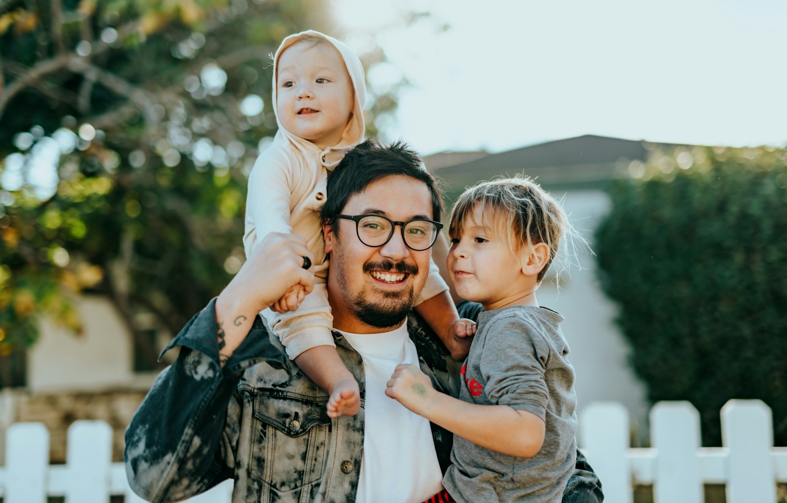 Father holding his two children outside their family home